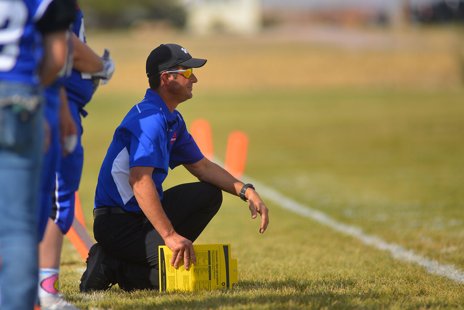 Kaycee High School head coach David Largent kneels on the sidelines